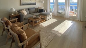 Ein Wohnzimmer mit einer Couch, Sesseln, einem Couchtisch und einem Gemälde an der Wand.