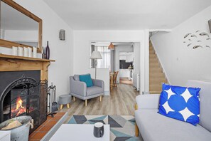 Un salon avec une cheminée, un canapé, une table basse et un escalier menant à une autre pièce.