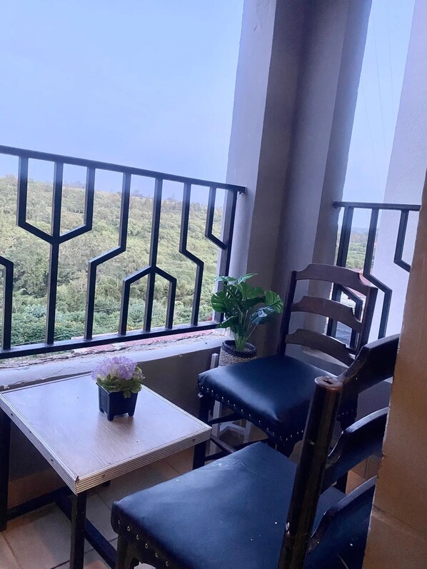 Un balcón con mesa de madera, dos sillas y una maceta.