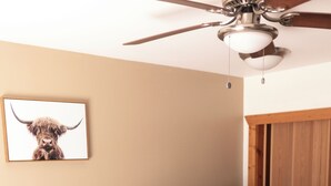 A bedroom with a wooden headboard, a bed with white bedding, a ceiling fan, and a wooden wardrobe. - CDA River Condo: Fishing, Sleding, Floating, Skiing (Kingston)