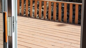 A wooden deck with a railing, overlooking a rocky hillside and dense foliage. - CDA River Condo: Fishing, Sleding, Floating, Skiing (Kingston)