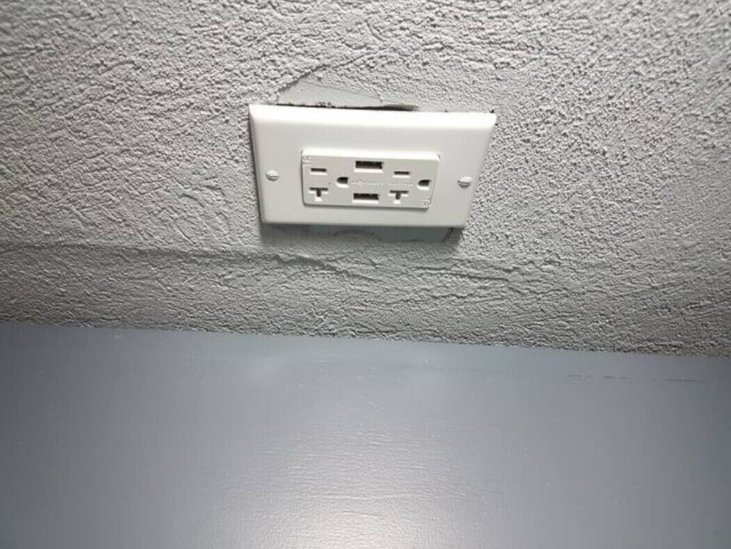 Eine weiße Steckdose an einer strukturierten Wand.