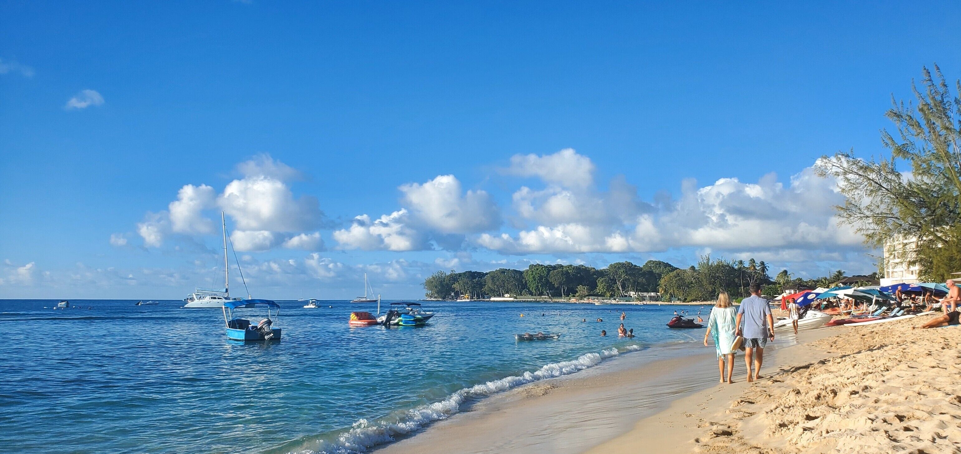 A beach with boats, people, and umbrellas.