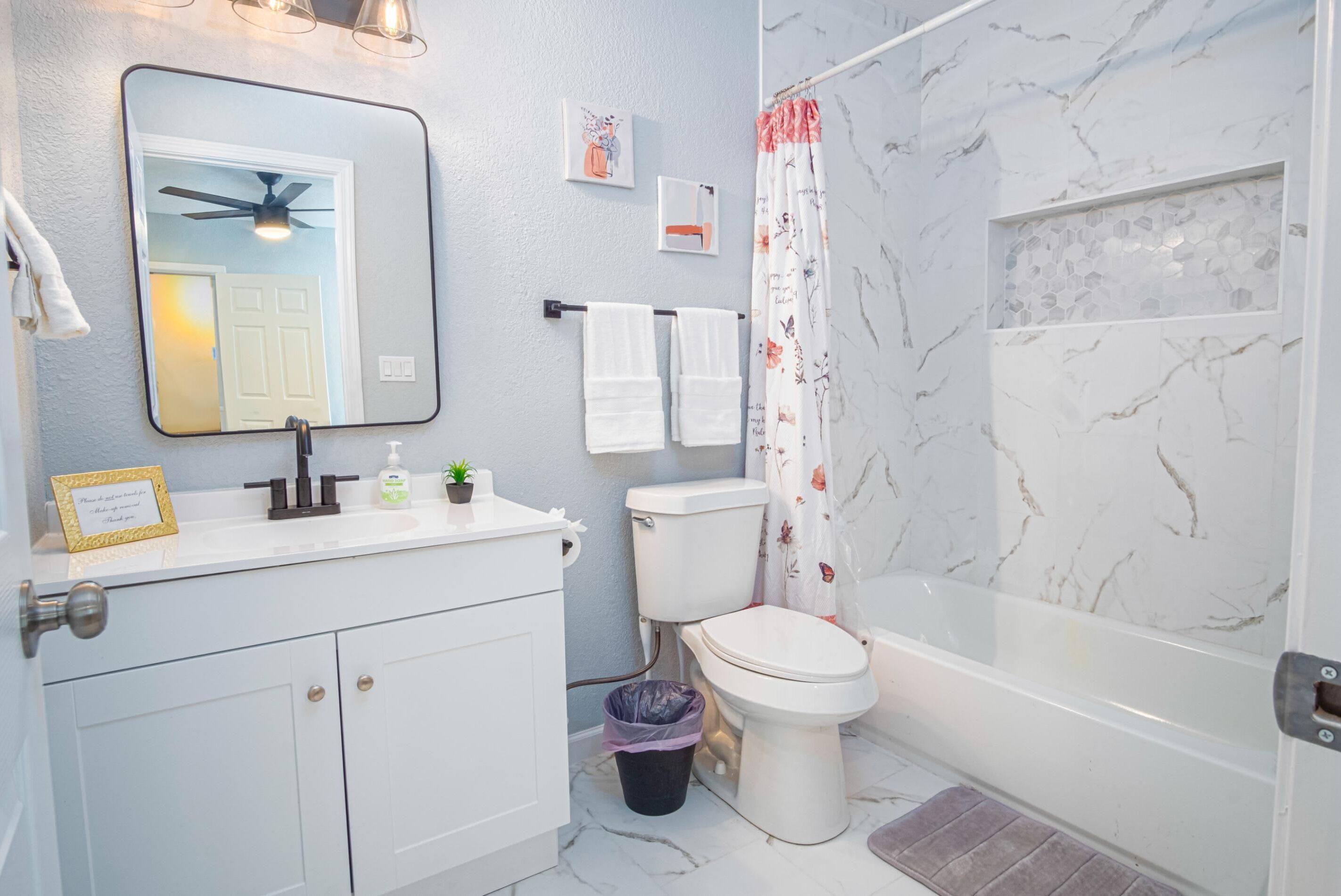 A bathroom with a toilet, sink, mirror, and shower.