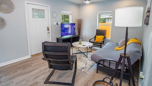 A living room with a sofa, two chairs, a coffee table, a TV, and a ceiling fan. - Charming 3br/1ba Close to Vibrant Downtown (San Antonio)