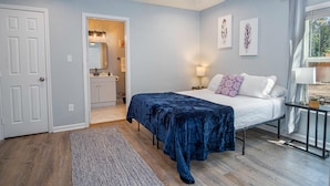 A bedroom with a bed, a ceiling fan, a nightstand, a lamp, and a window with curtains. - Charming 3br/1ba Close to Vibrant Downtown (San Antonio)