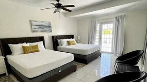 A hotel room with two beds, a ceiling fan, a window with curtains, and a chair. - Vistamar 5-bedroom Villa with pool (Carolina)