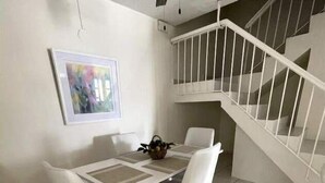 A dining area with a white table and chairs, a ceiling fan, a staircase with a white railing, and a framed picture on the wall. - Vistamar 5-bedroom Villa with pool (Carolina)