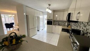 A modern kitchen with white cabinets, a black countertop, and a tiled backsplash. - Vistamar 5-bedroom Villa with pool (Carolina)