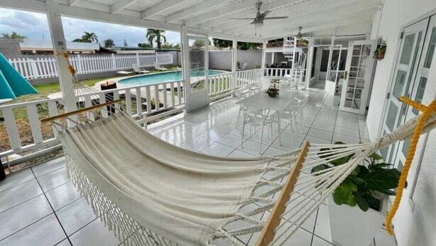 A covered patio with a hammock, a pool, and a dining area. - Vistamar 5-bedroom Villa with pool (Carolina)