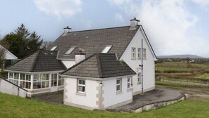 A two-story house with a sloped roof, a conservatory, and a small garden area. - Gunn's Cottage (Enniskillen)