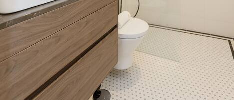 A modern bathroom with a white sink, a mirror, and a shower area.