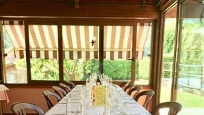 Une longue table à manger, dressée avec des verres à vin, des couverts et des serviettes, et offrant une vue sur la verdure environnante.