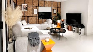 A modern living room with a sectional sofa, a flat-screen TV, and a minimalist decor. - Super Stylish 4BR Retreat in the Heart of Las Olas (Fort Lauderdale)