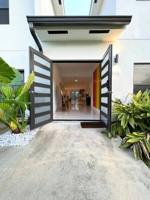 A modern house with a large open doorway leading to a spacious interior.