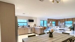 A modern kitchen with a dining area, featuring a wooden table and chairs, a built-in oven, and a large window providing natural light. - Super Stylish 4BR Retreat in the Heart of Las Olas (Fort Lauderdale)