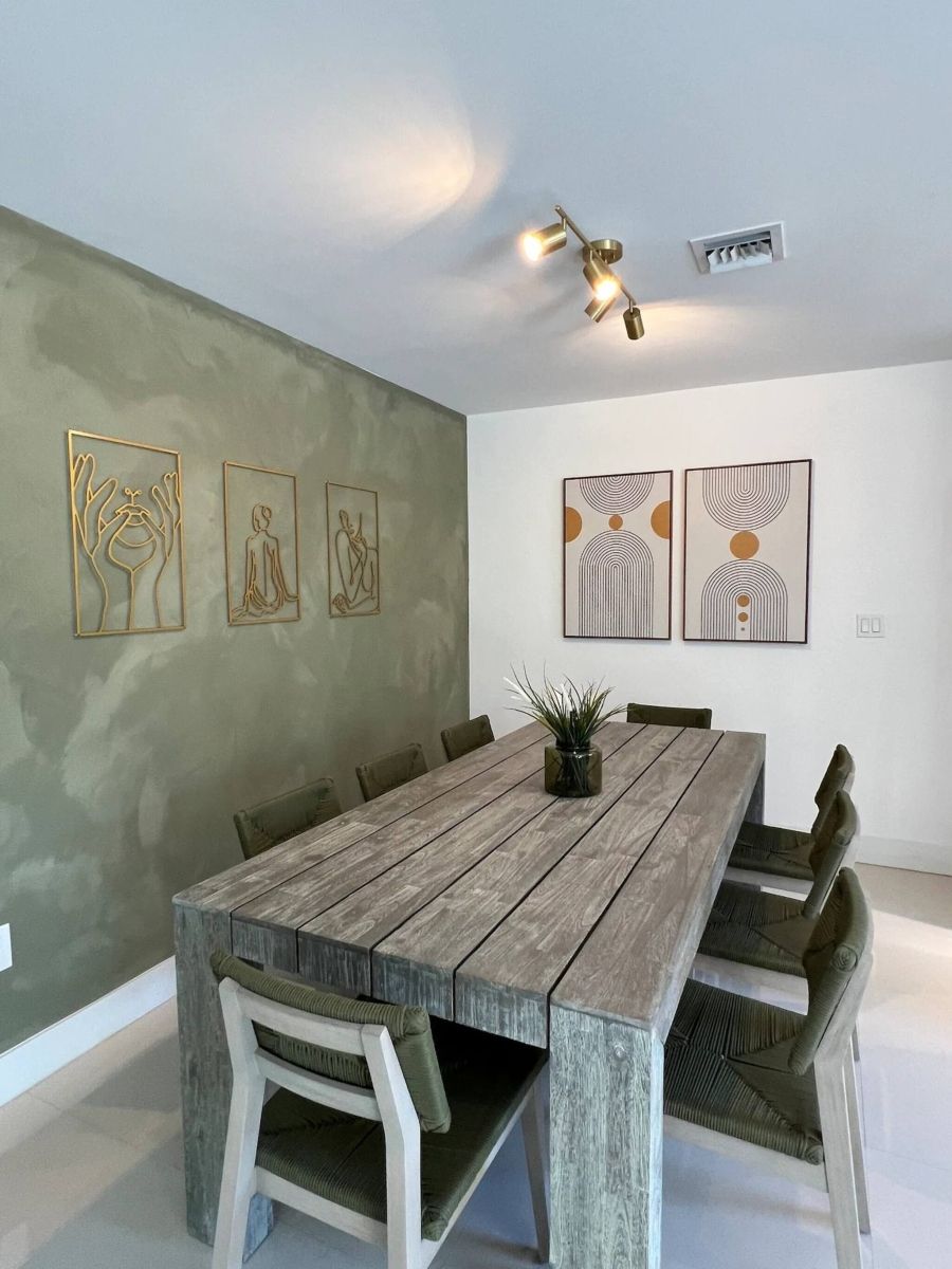 Un espace repas avec une table et des chaises en bois, entouré d’œuvres d’art abstraites accrochées aux murs.