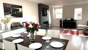 Un comedor moderno con una mesa de vidrio, sillas blancas y un jarrón con flores.