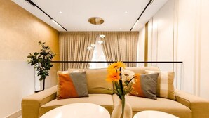 A modern living room with a beige sofa, two round tables, and a vase with flowers. - Ebs legend white limited (Accra)