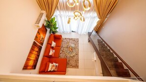 A modern living room with a sofa set, a plant, and a staircase. - Ebs legend white limited (Accra)