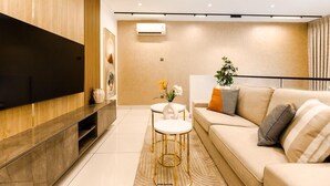 A modern living room with a flat-screen TV, a sofa, two small tables, and a decorative plant. - Ebs legend white limited (Accra)