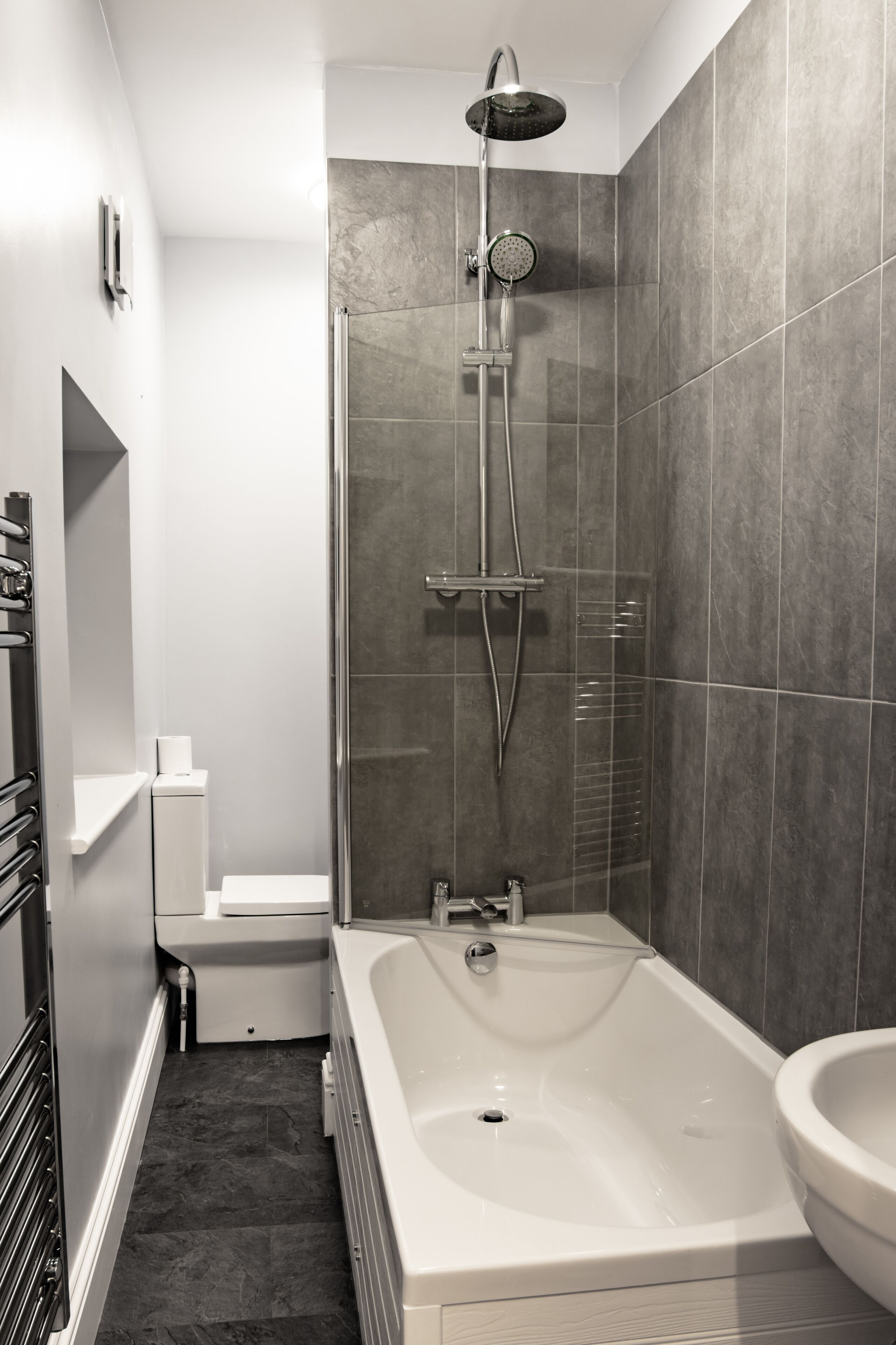 A modern bathroom with a bathtub, shower, and toilet.