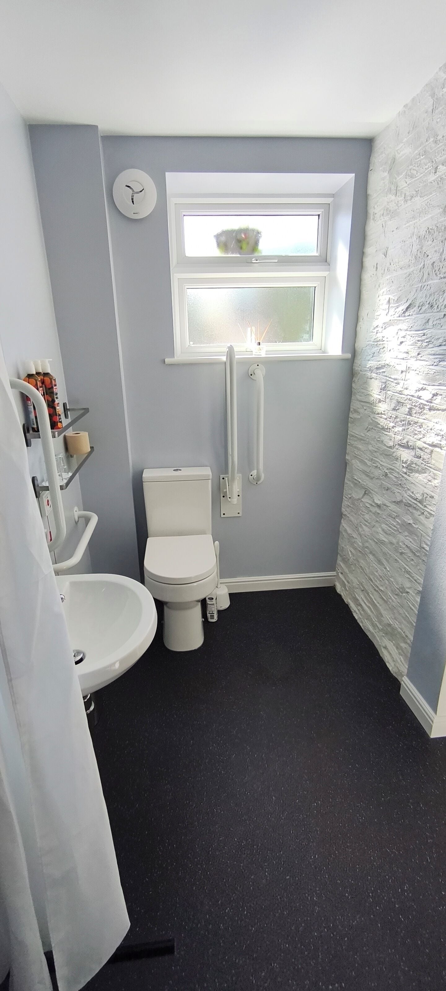 Une salle de bain avec des toilettes, un lavabo et une fenêtre.