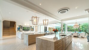 Een moderne keuken met een groot eiland, houten kasten en hanglampen.