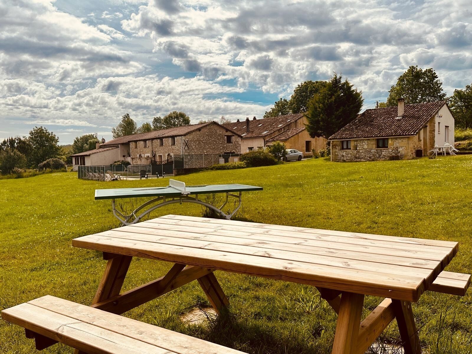 A picnic table in a grassy field with stone buildings in the background.