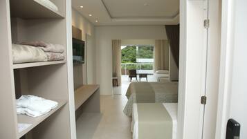 Habitación de hotel con cama, escritorio y armario. Tiene un balcón con vista a árboles.