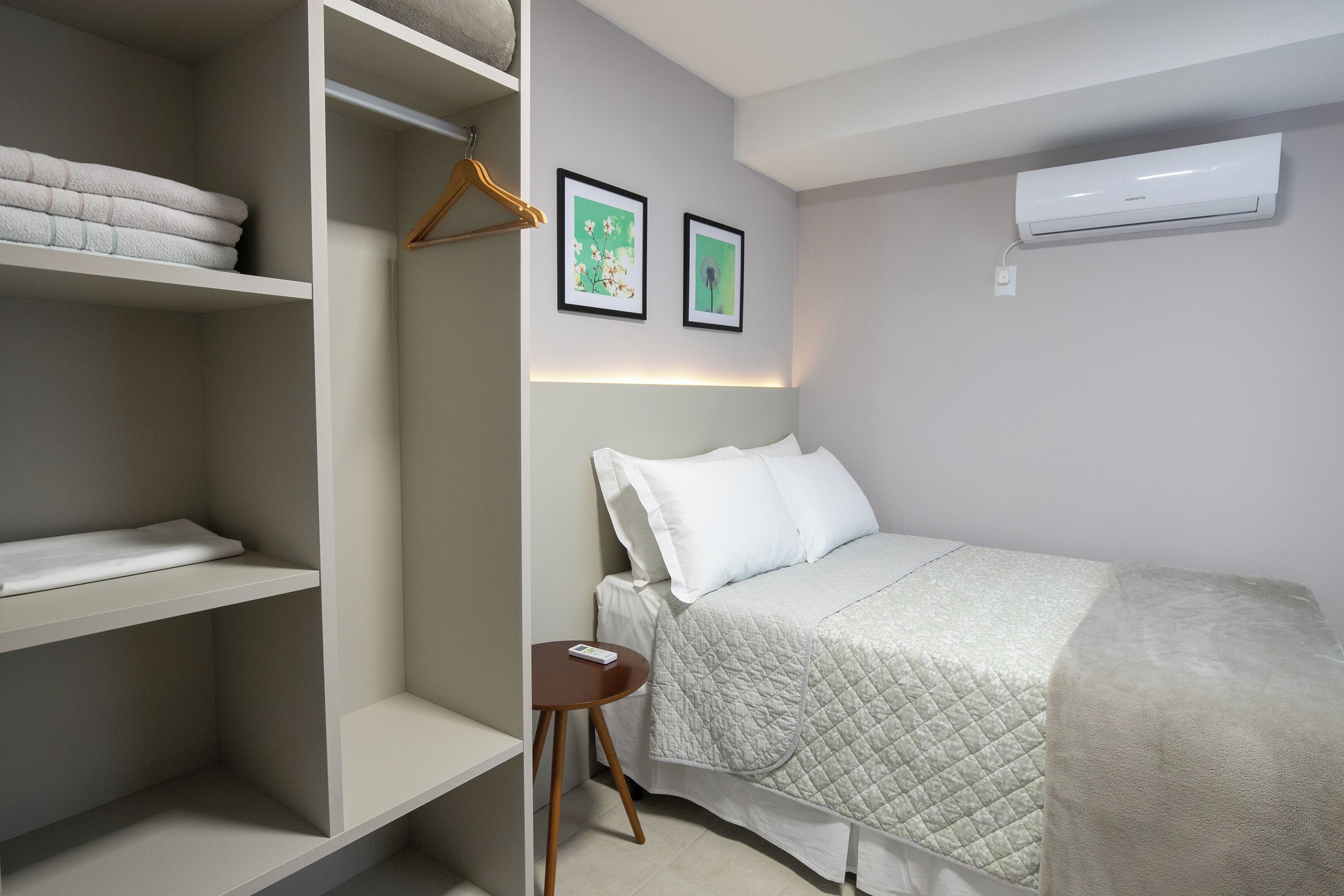 Una camera da letto con un letto, un armadio e un tavolino. In parete, due quadri.