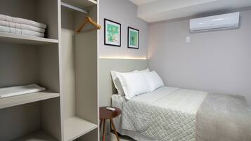 Una camera da letto con un letto, un armadio e un tavolino. In parete, due quadri.
