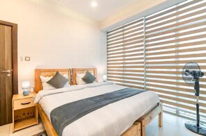 Enjoy a restful stay in this stylish room featuring a single bed, bedside table, and large window with horizontal blinds.