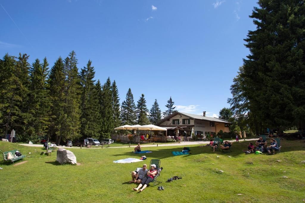 A lodge with outdoor seating and a large rock in the foreground.