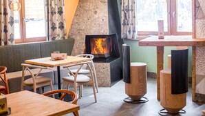 A cozy indoor seating area with a fireplace, wooden furniture, and large windows. - Rifugio La Montanara (Molveno)
