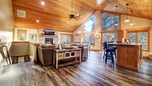 A spacious living room with a fireplace, a dining area, and a kitchen with large windows. - Pet Friendly + Pool Table + Shuffle Board + Arcade Game (South Lake Tahoe)