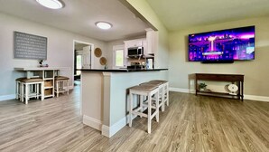 Una cocina moderna con una isla central, taburetes de bar y una zona de comedor.