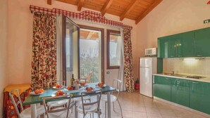 A dining area with a table set for four, a refrigerator, and green cabinets.