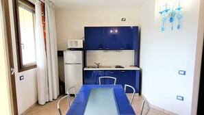 A compact kitchen with a microwave, cabinets, and a dining table with chairs.