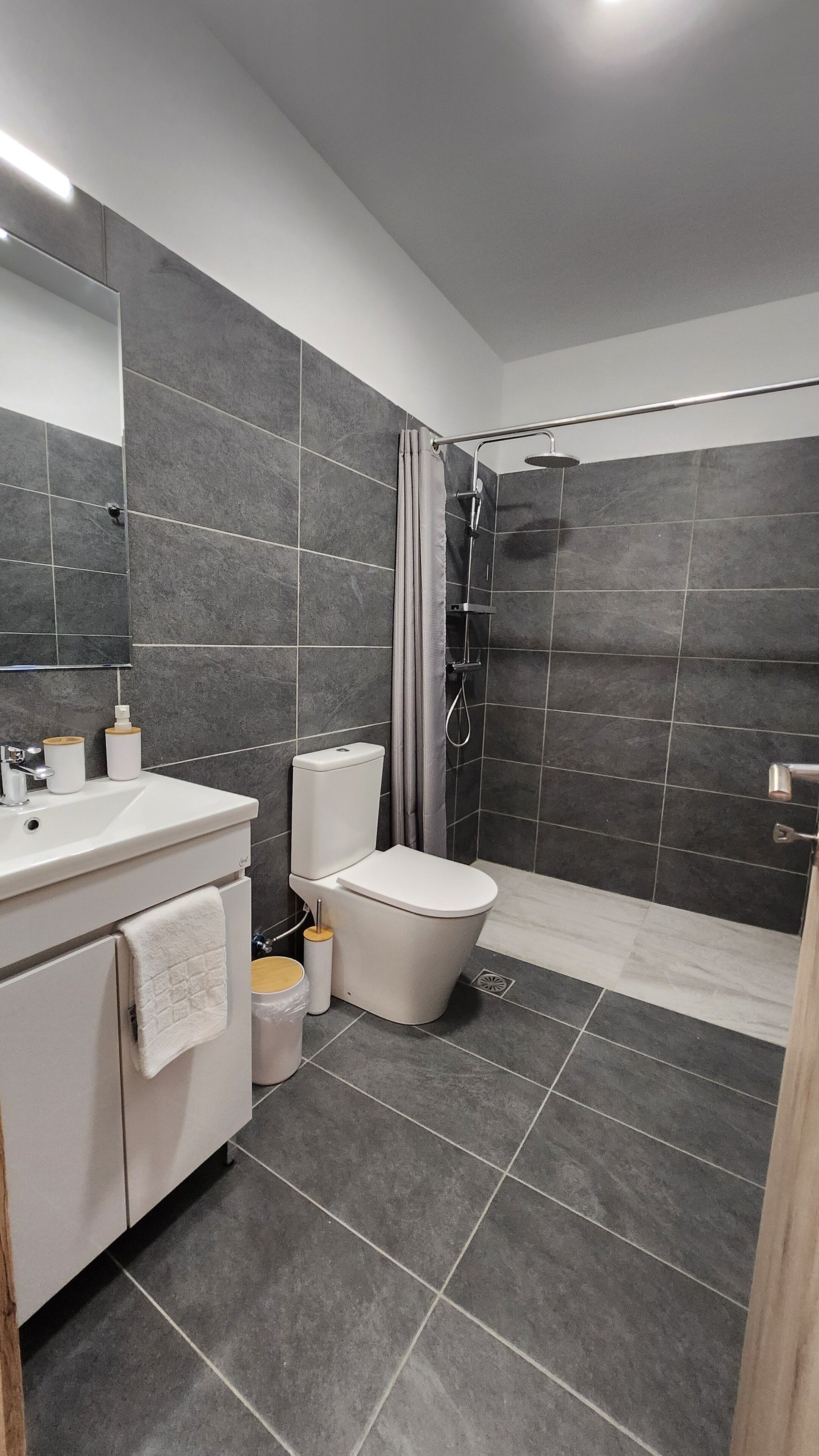 Une salle de bain moderne avec un meuble-lavabo blanc, des toilettes et un espace douche.