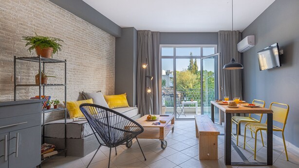 Een moderne woonruimte met een bank, eettafel, stoelen, salontafel, boekenplank en een potplant.
