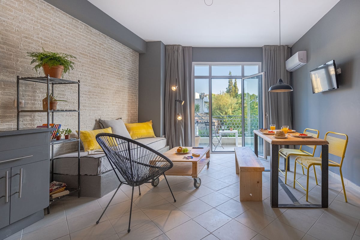 Un espace de vie moderne comprenant un canapé, une table à manger, des chaises, une table basse, une bibliothèque et une plante en pot.