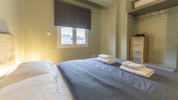 Een slaapkamer met een bed, een raam met zonwering, een houten garderobe en een radiator.