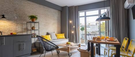 A modern kitchen with grey cabinets, a black chair, and a dining table with yellow chairs.
