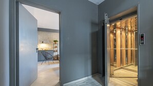 Een moderne lift met een metalen afwerking en een digitaal bedieningspaneel.