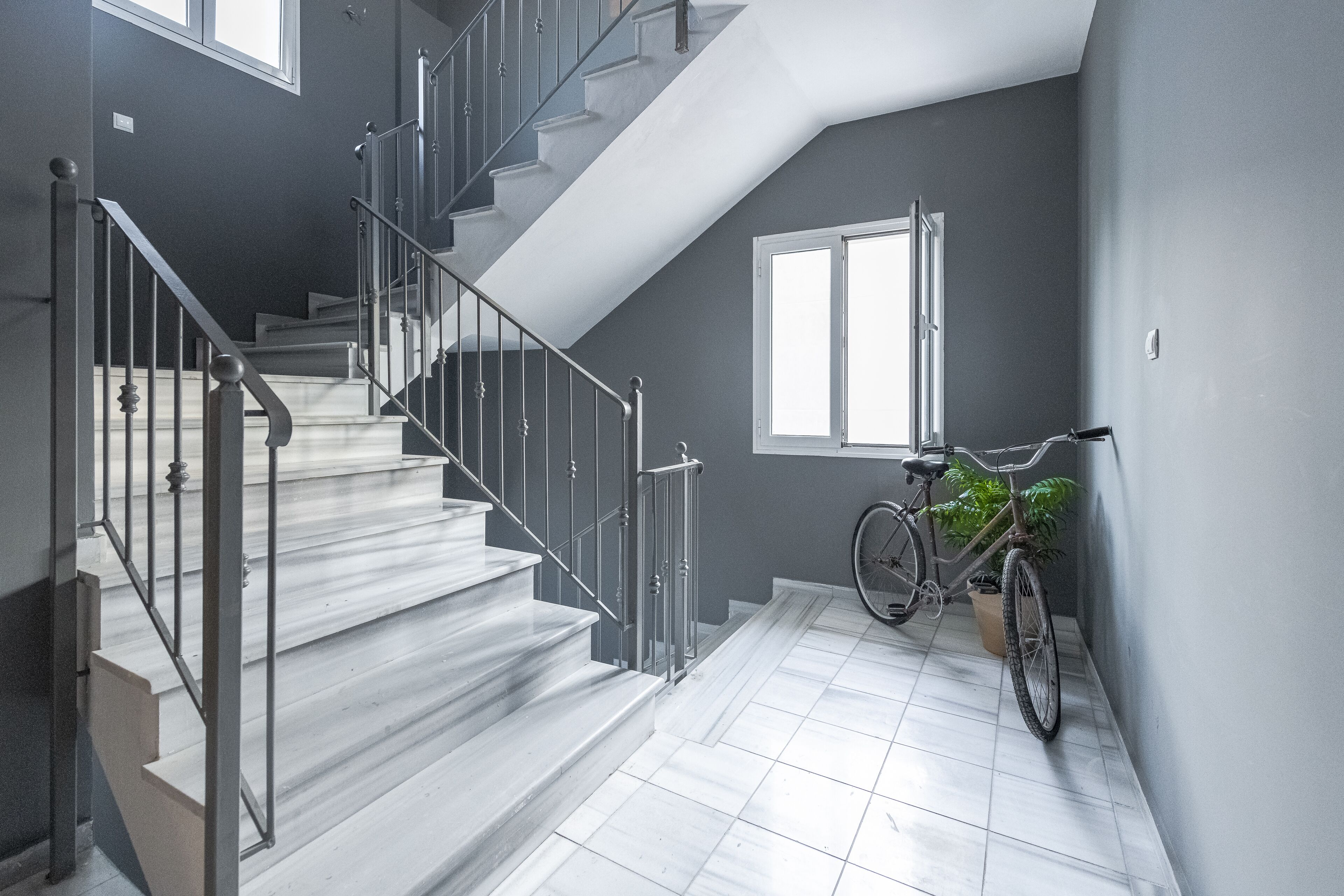 Un escalier avec des rampes en métal et un vélo appuyé contre un mur.