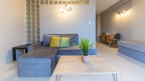 Een moderne woonkamer met een grijze modulaire bank, een houten salontafel en een potplant.