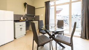 Een moderne keuken met een koelkast, kasten en een eethoek met een glazen tafel en stoelen.