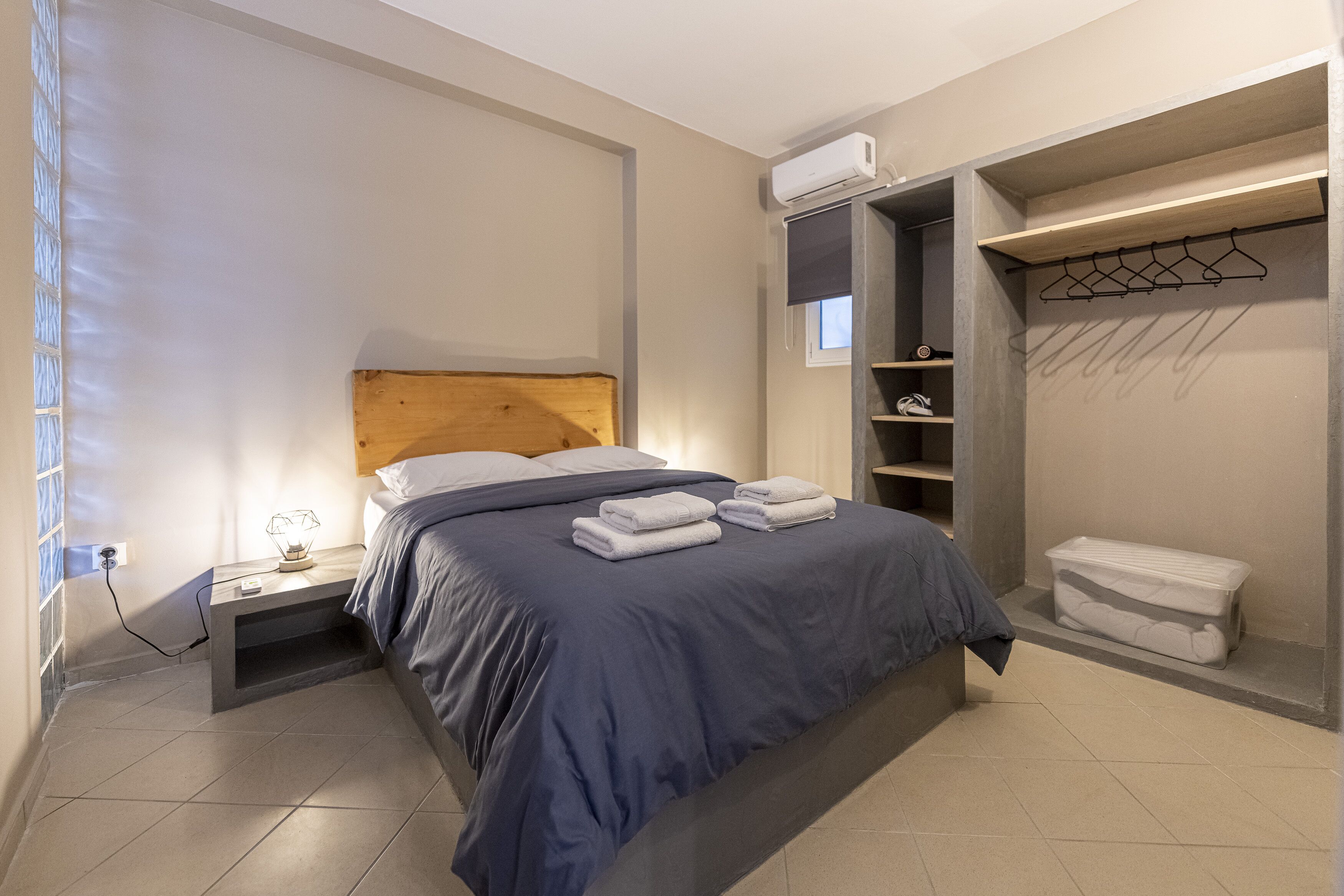 A bedroom with a bed, bedside table, and a built-in wardrobe with shelves and a hanging rack.