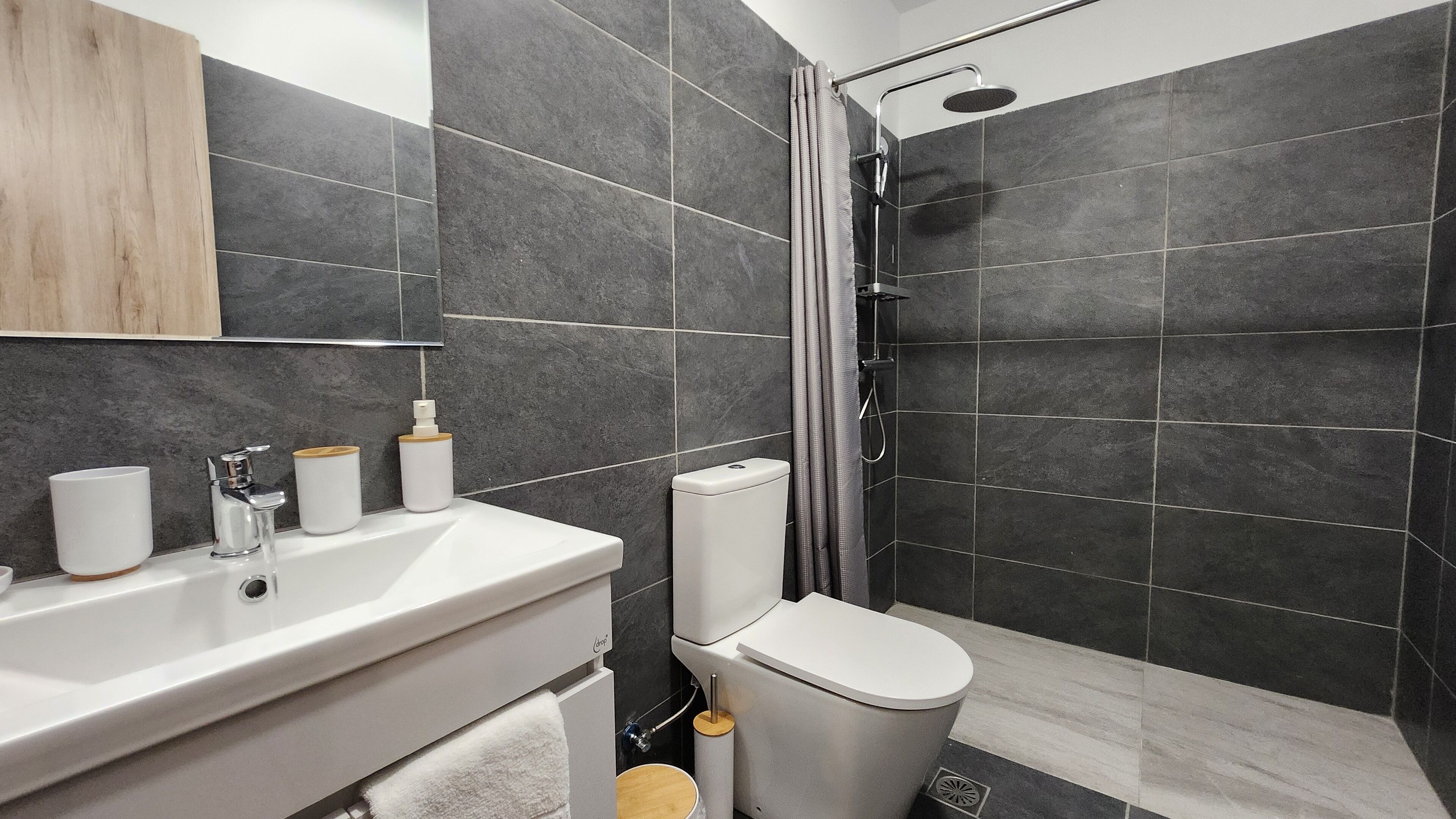A modern bathroom with a shower, toilet, and sink.